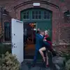 Et tango-dansende par står tett omslynget utenfor inngangsdøren til Sentralbadet litteraturhus. Døren er åpen. Foto.
